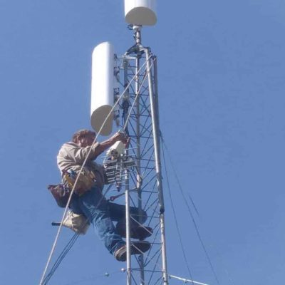 Leonard Smith climbs a tower to install a set of antennas