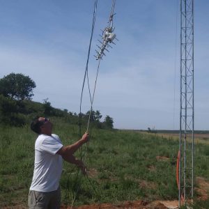 Travis Ridgeway hoists up a rope carrying a small UHF antenna.
